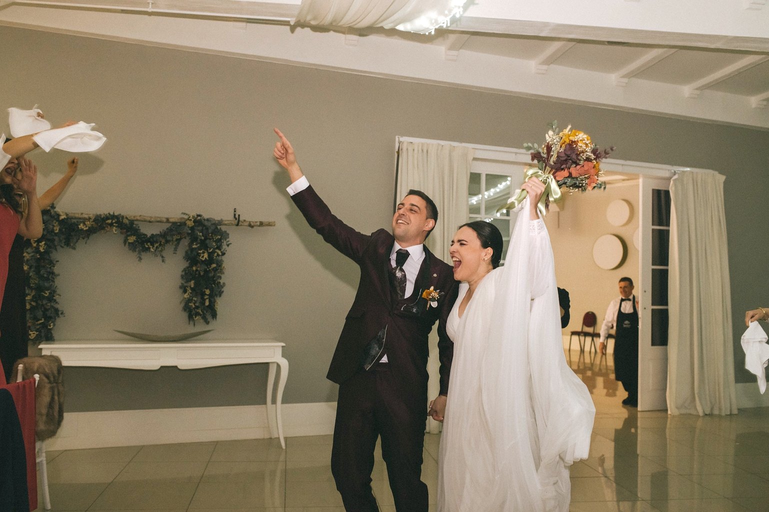 Los novios entran al banquete entre vítores; ella levanta el ramo de flores de otoño