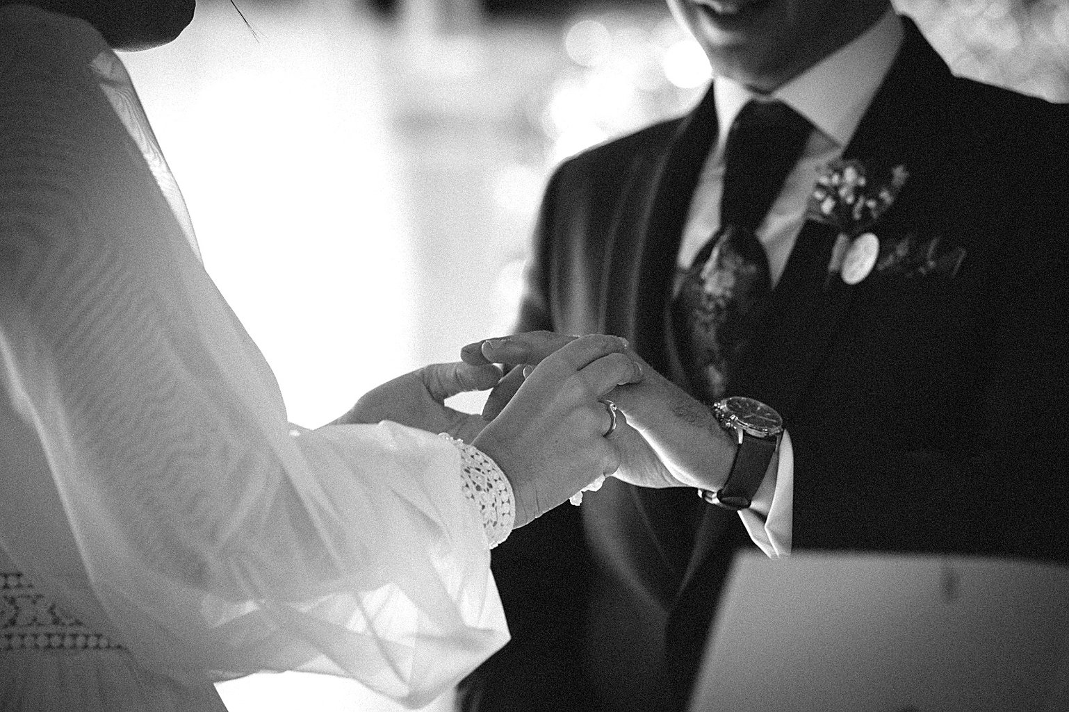 Retrato en blanco y negro del novio ajustándose el reloj, con la flor en la solapa